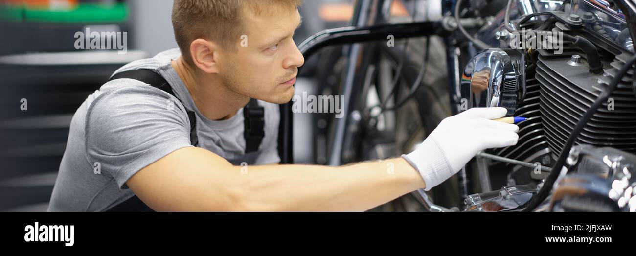 A man in the garage is checking a motorcycle Stock Photo
