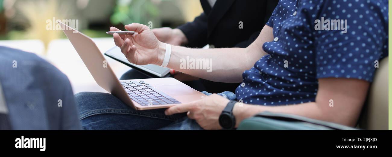 A man with a laptop and a woman with a tablet are talking Stock Photo