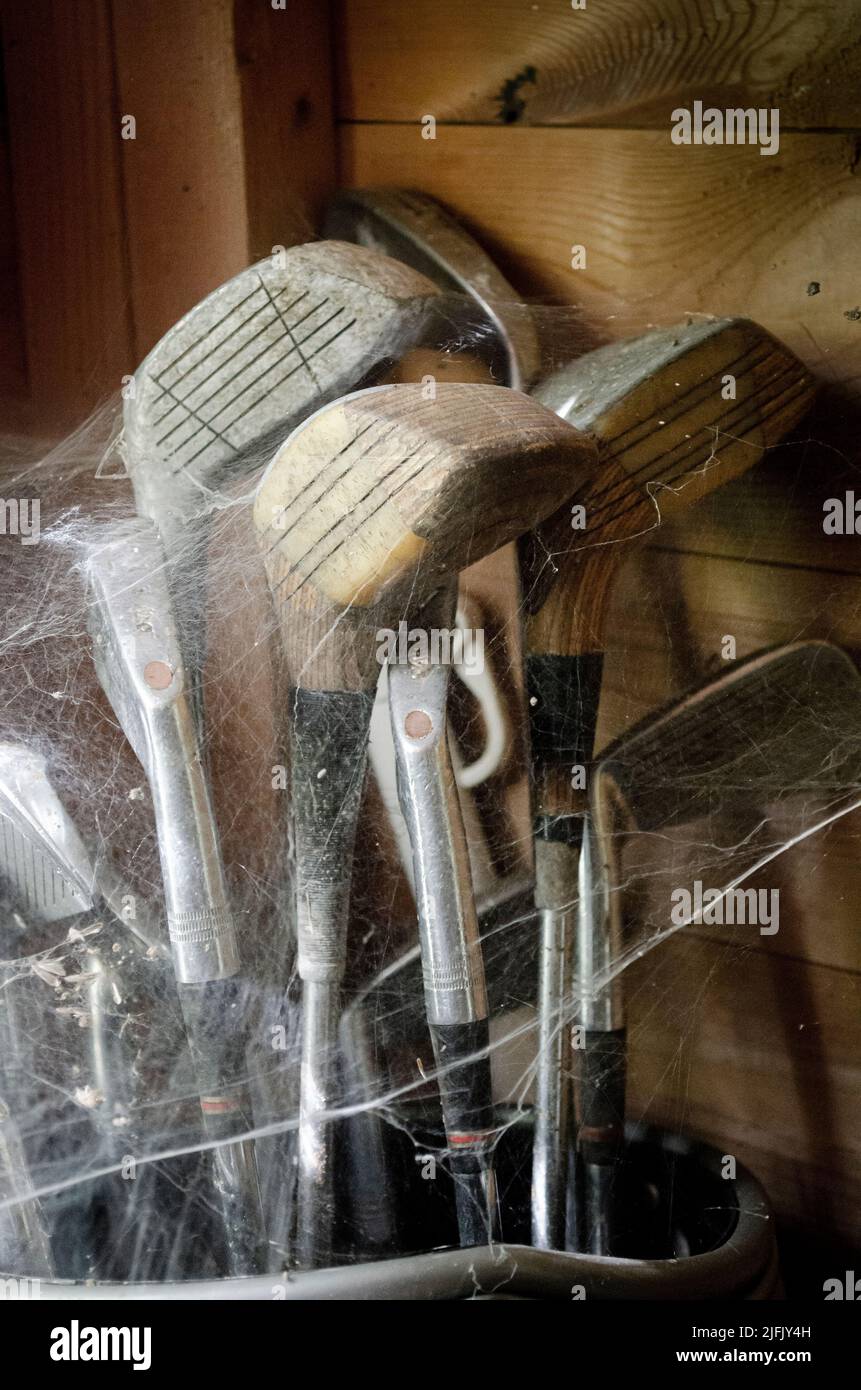 A set of golf clubs have been covered in cobwebs giving a concept of