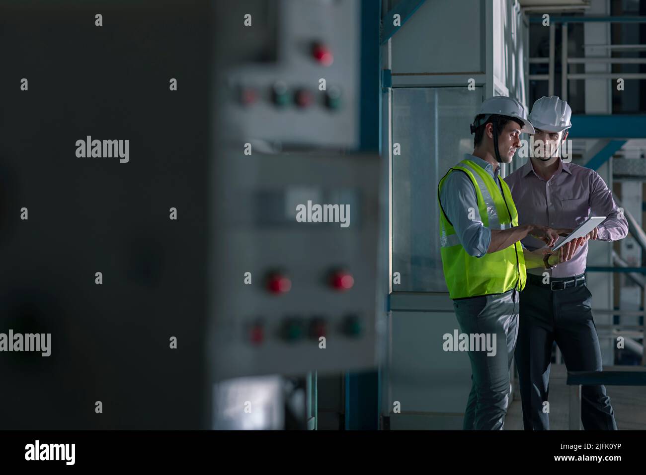 Two mid adult man working on digital tablet in the factory Stock Photo