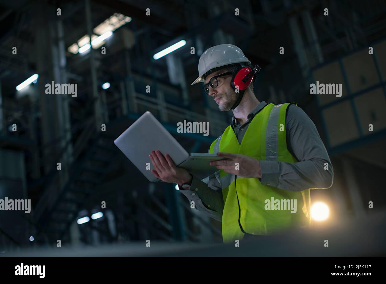 Mid adult man working on the laptop in the factory Stock Photo
