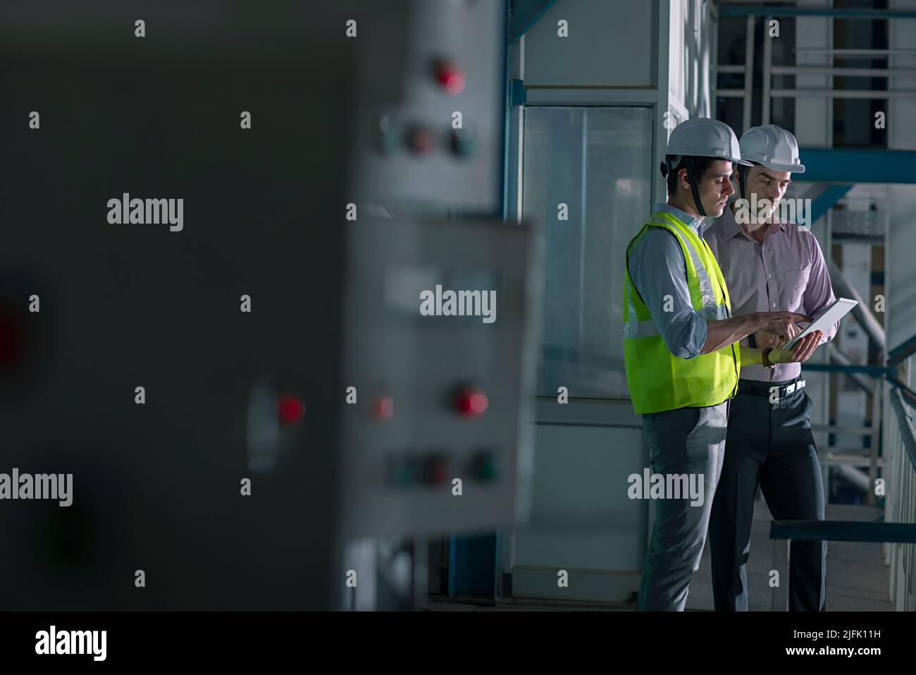 Two mid adult man working on digital tablet in the factory Stock Photo