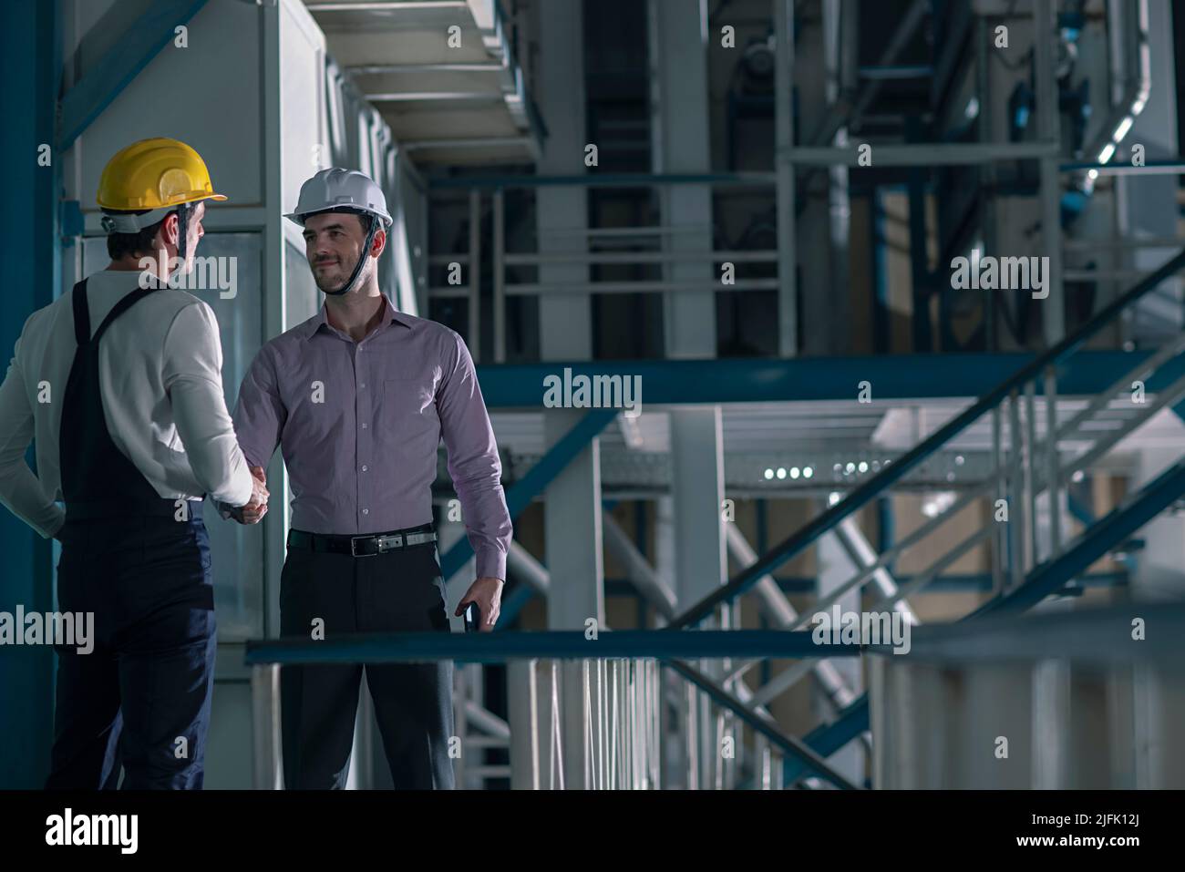 Mid adult man shaking hands with his colleague in the factory Stock Photo