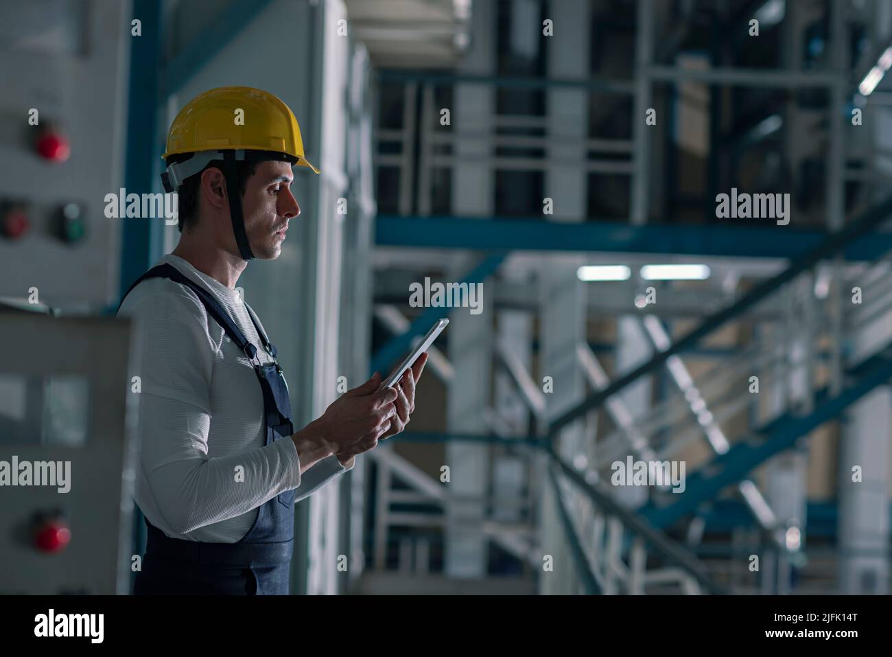 Side profile of a mid adult man working on the digital tablet in the factory Stock Photo