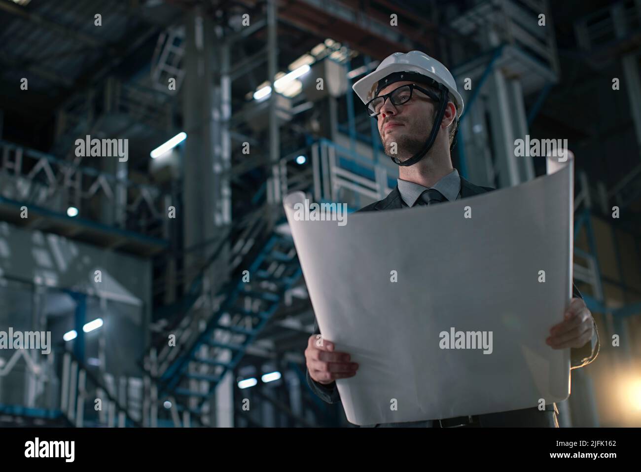 Mid adult man holding a blueprint in a factory  Stock Photo