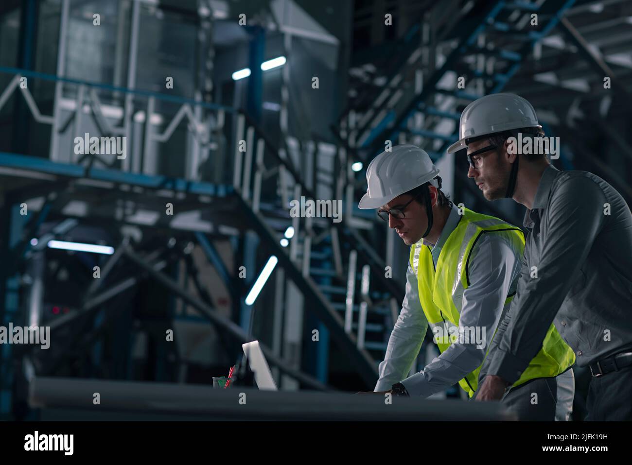 Two mid adult man working on the laptop in the factory Stock Photo