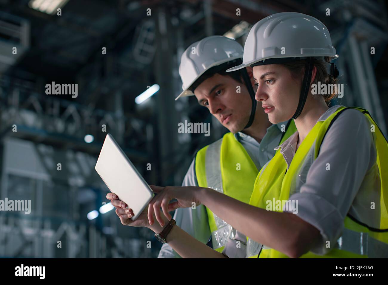 Mid adult man with a young woman working on the digital tablet in the factory Stock Photo