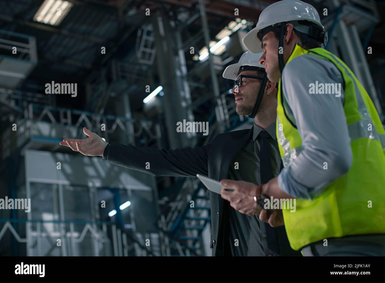 Mid adult man discussing with a businessman in the factory Stock Photo