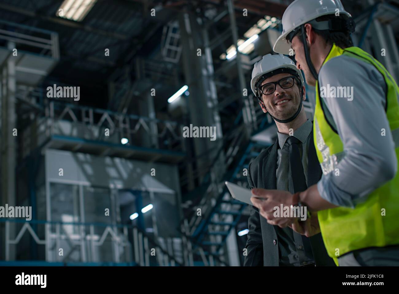 Mid adult man talking to a businessman in the factory  Stock Photo