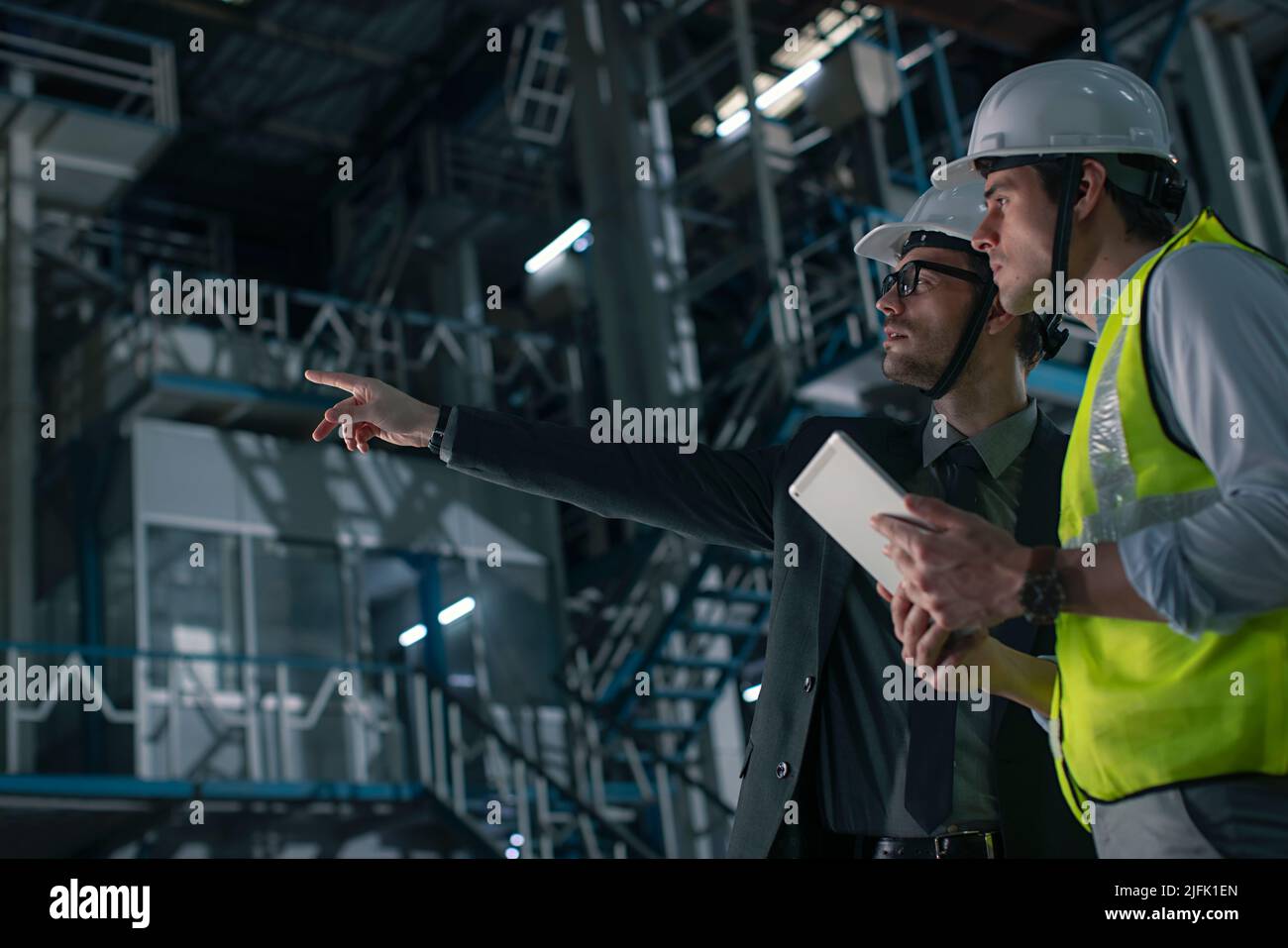 Mid adult man discussing with a businessman in the factory  Stock Photo