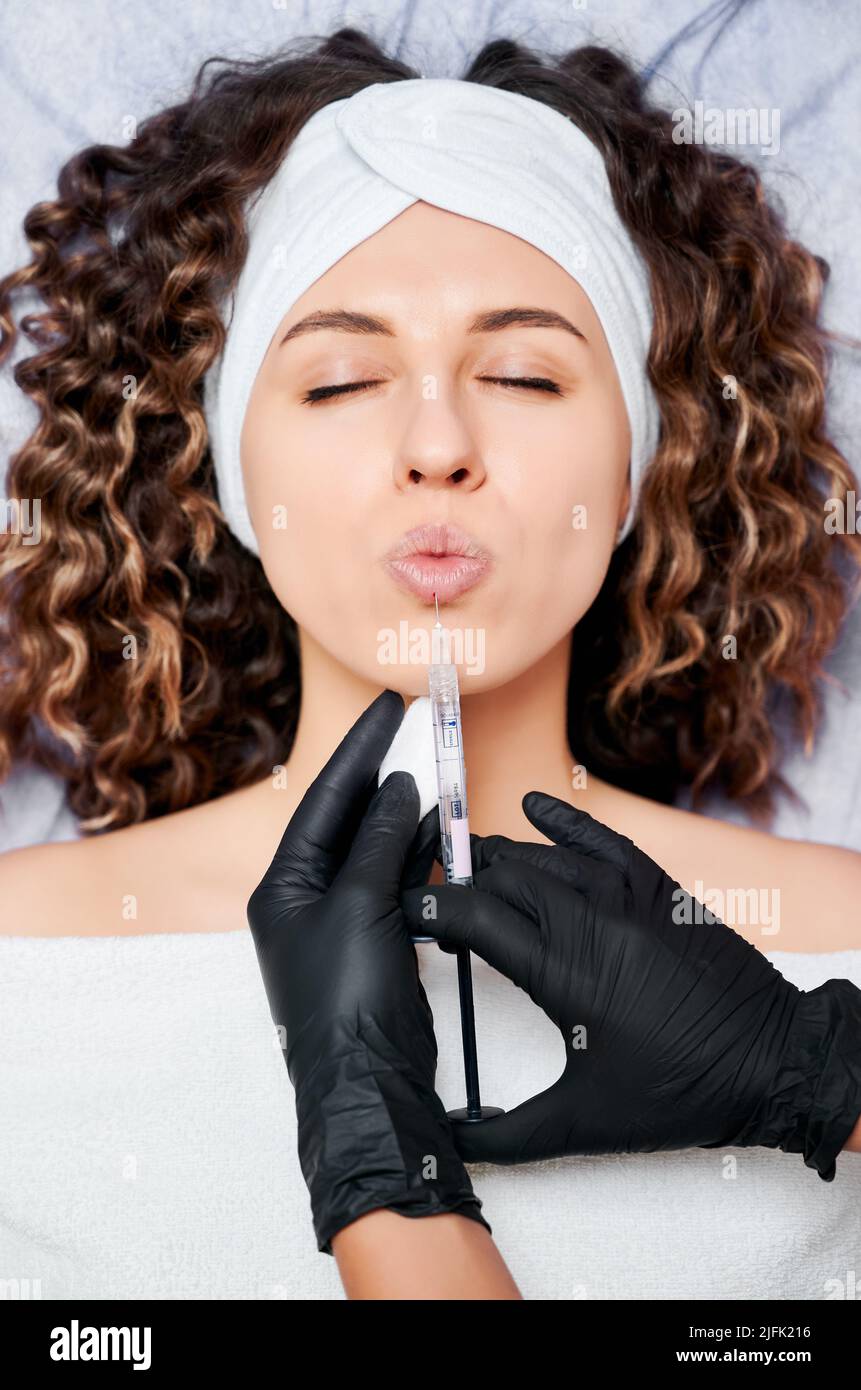 Close up of beautician in black rubber gloves doing lip augmentation