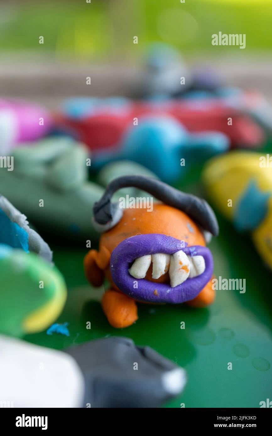 A vertical view of an orange-colored clay monster character Stock Photo