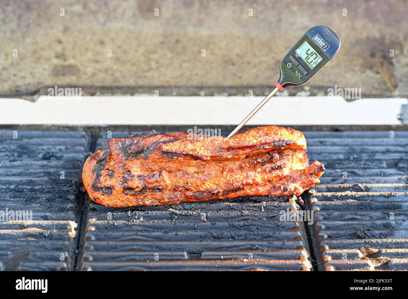 Meat thermometer stucked in to pork tenderloin on grill Stock Photo Alamy