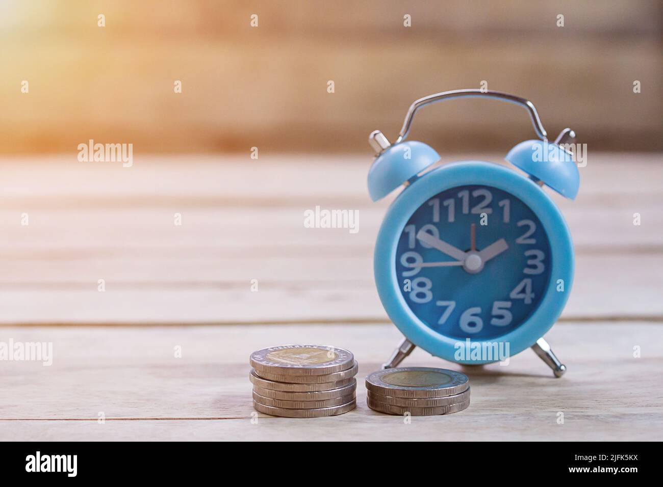 Coins,alram clock and pencil with empty notebook on wood table background. Office desk with money coins and business financial planning concept Stock Photo