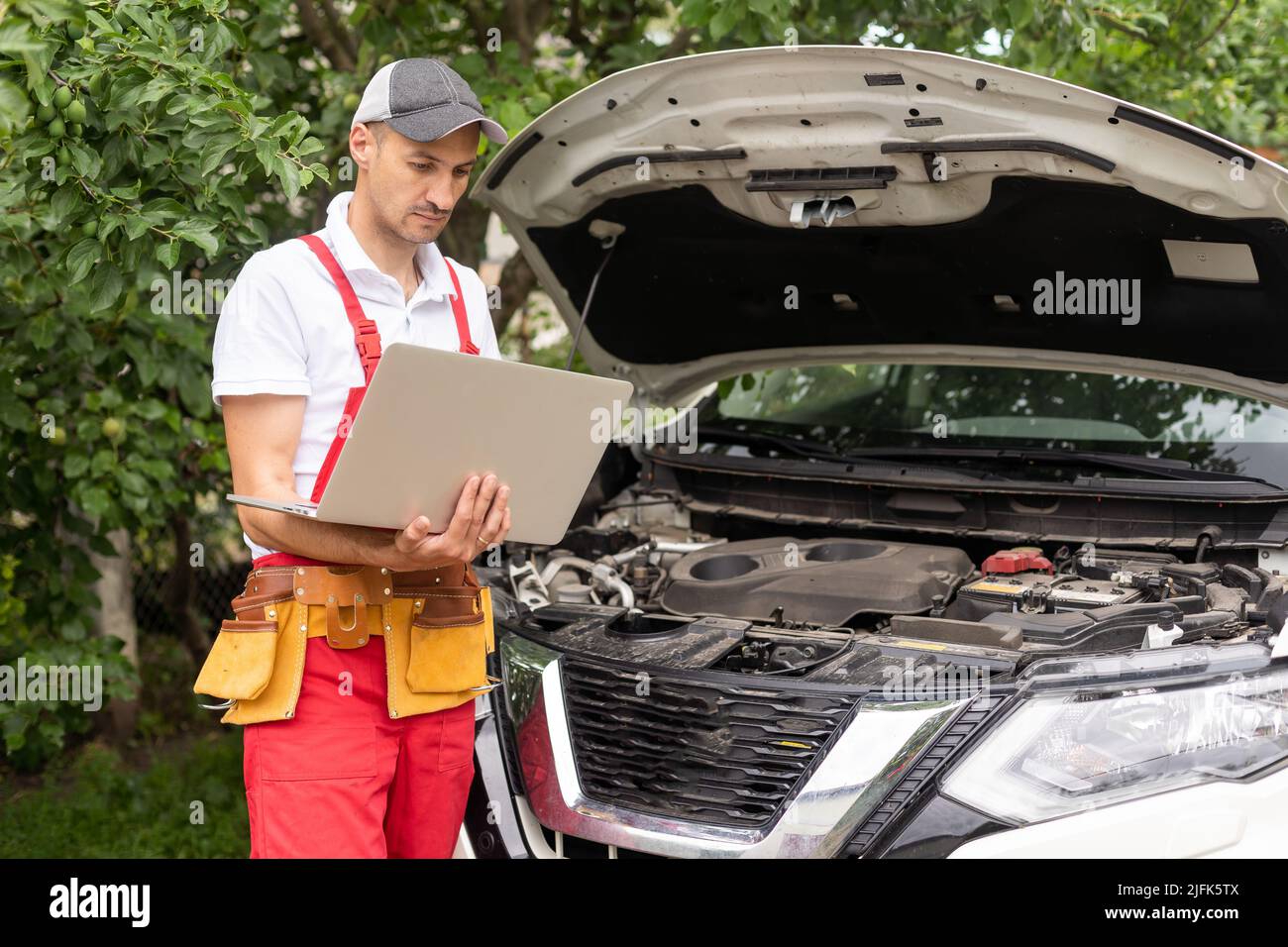 Mechanic with laptop near car engine. Modern car diagnostic program on