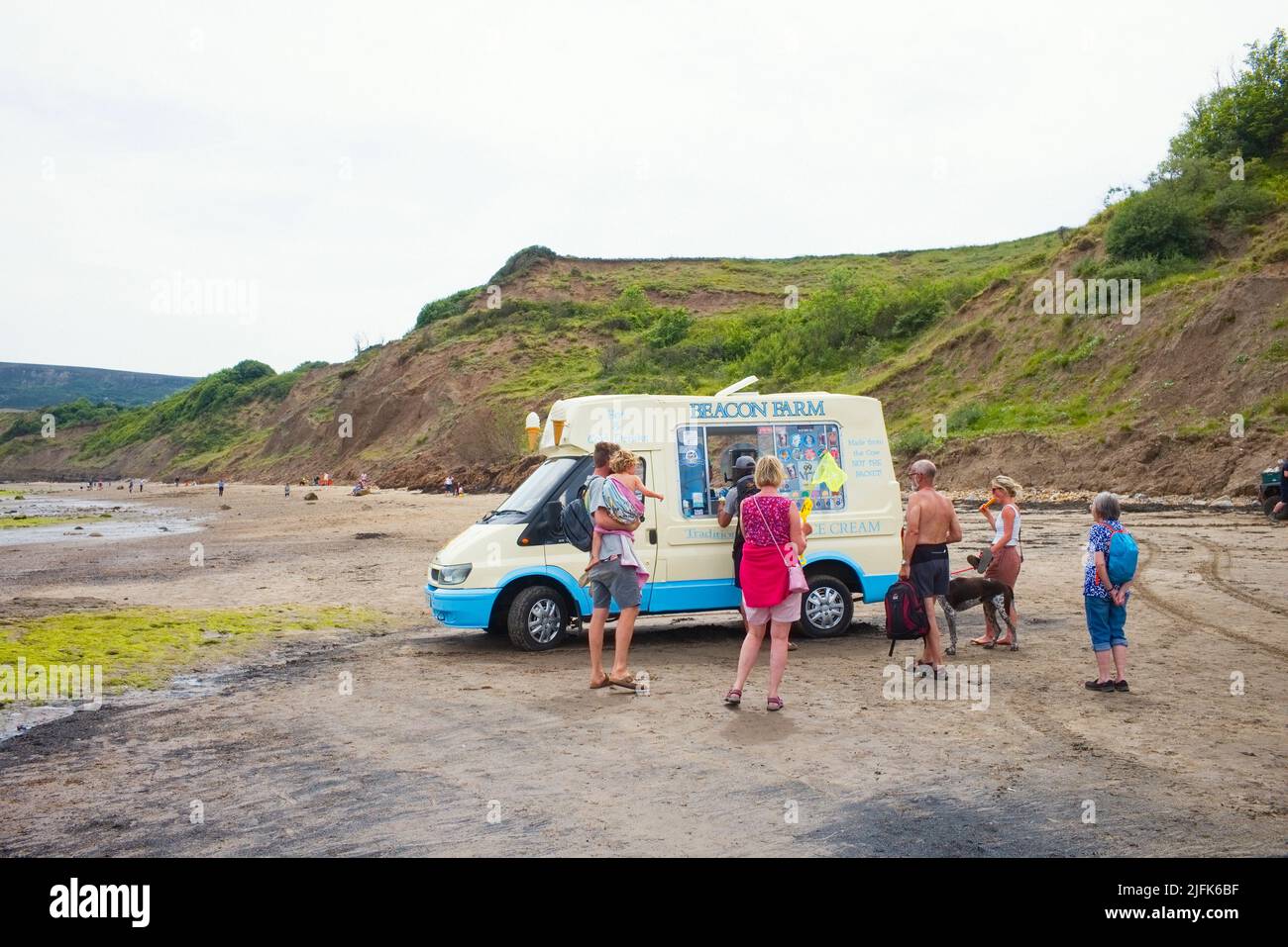 People queueing for ice creams from a van on the beach at Robin Hood's Bay, North Yorkshire Stock Photo