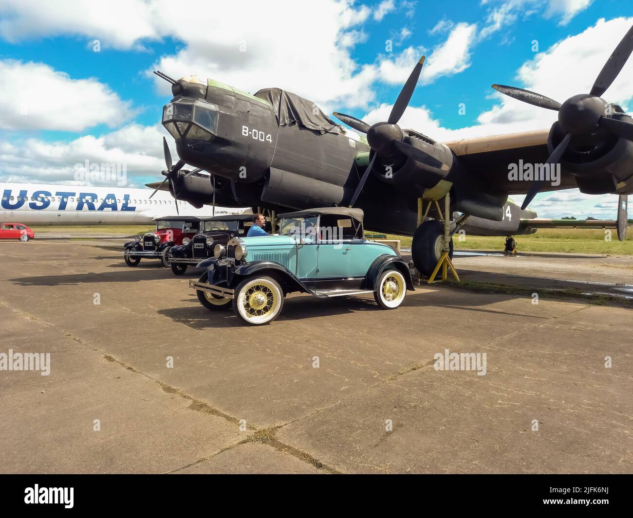Old cyan Ford Model A coupe roadster 1927-1937 in front of a WWII Avro Lincoln MKII four-engined bomber 1944-1967. Classic car show. Copyspace. Stock Photo