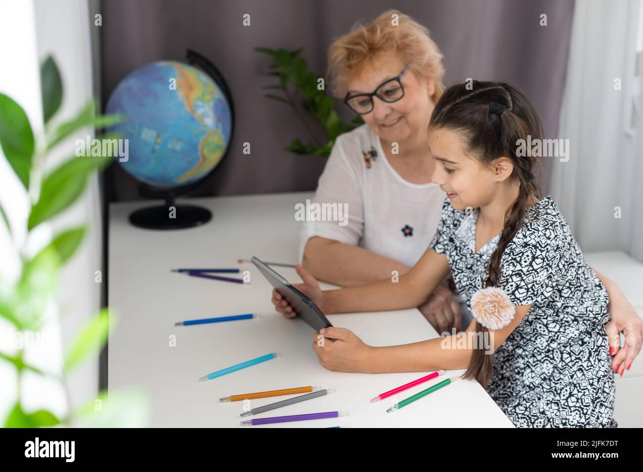 Cute little girl with her grandmother looking at tablet at home Stock ...