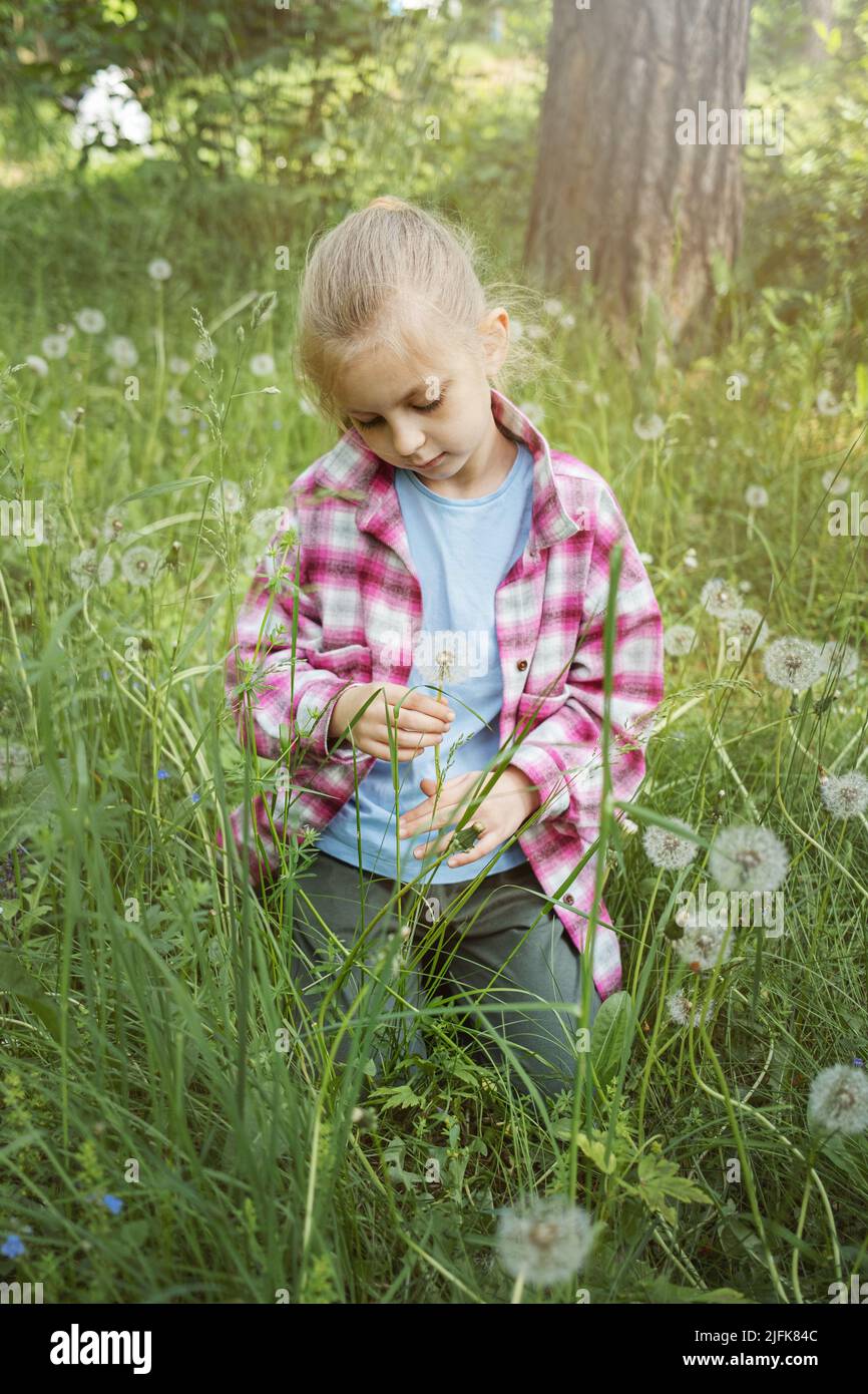 Image of pretty little girl sitting on dandelions field, happy cheerful ...