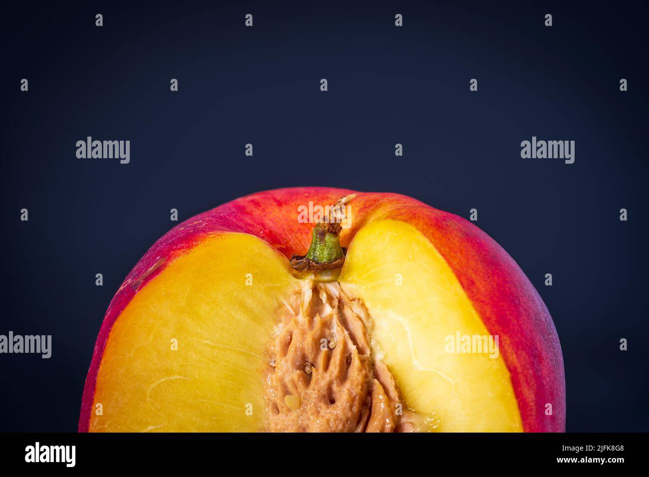 Ripe single nectarine fruit cut open with stone seed inside over dark