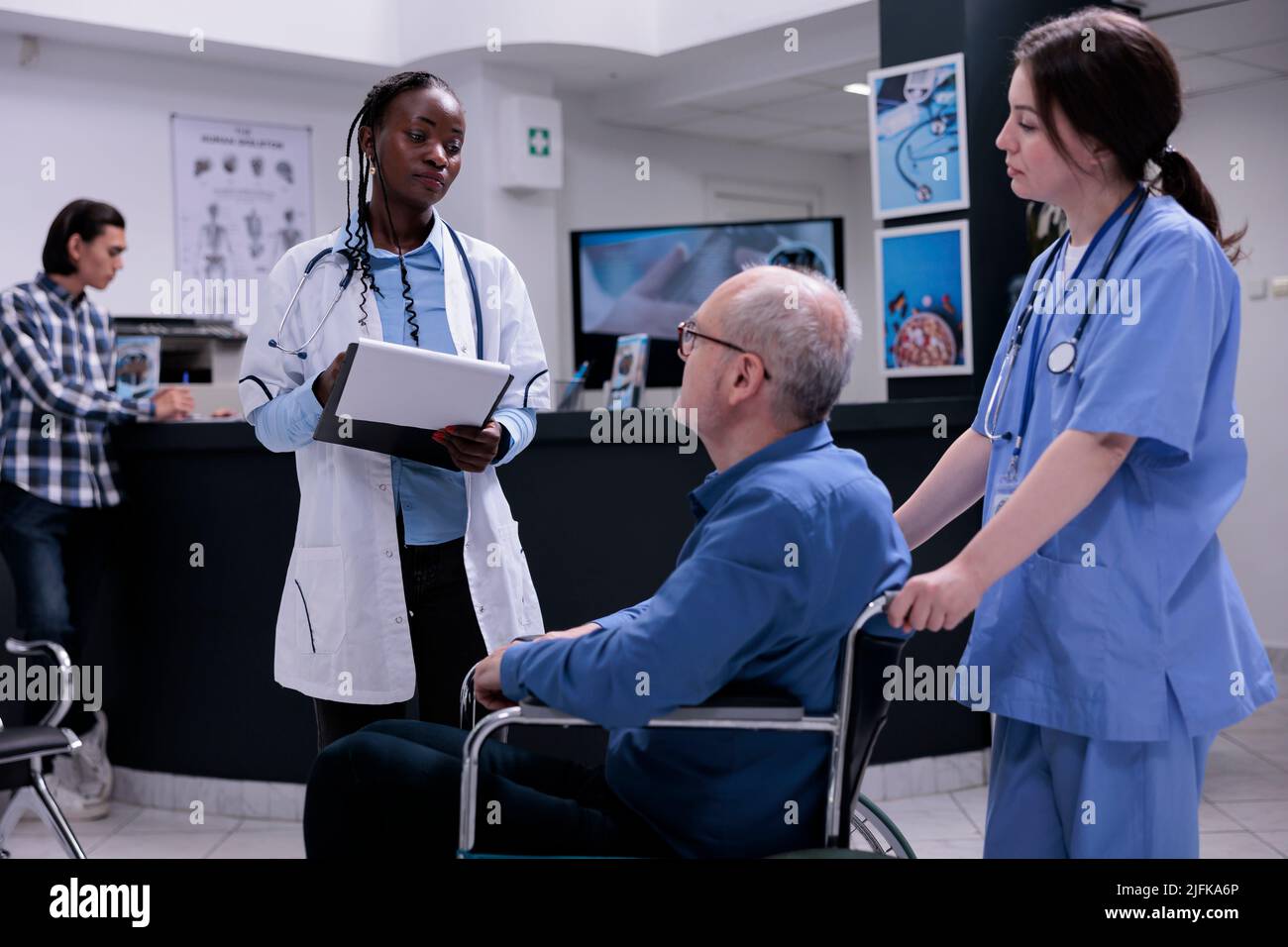 Older man living with disability in hospital reception talking with