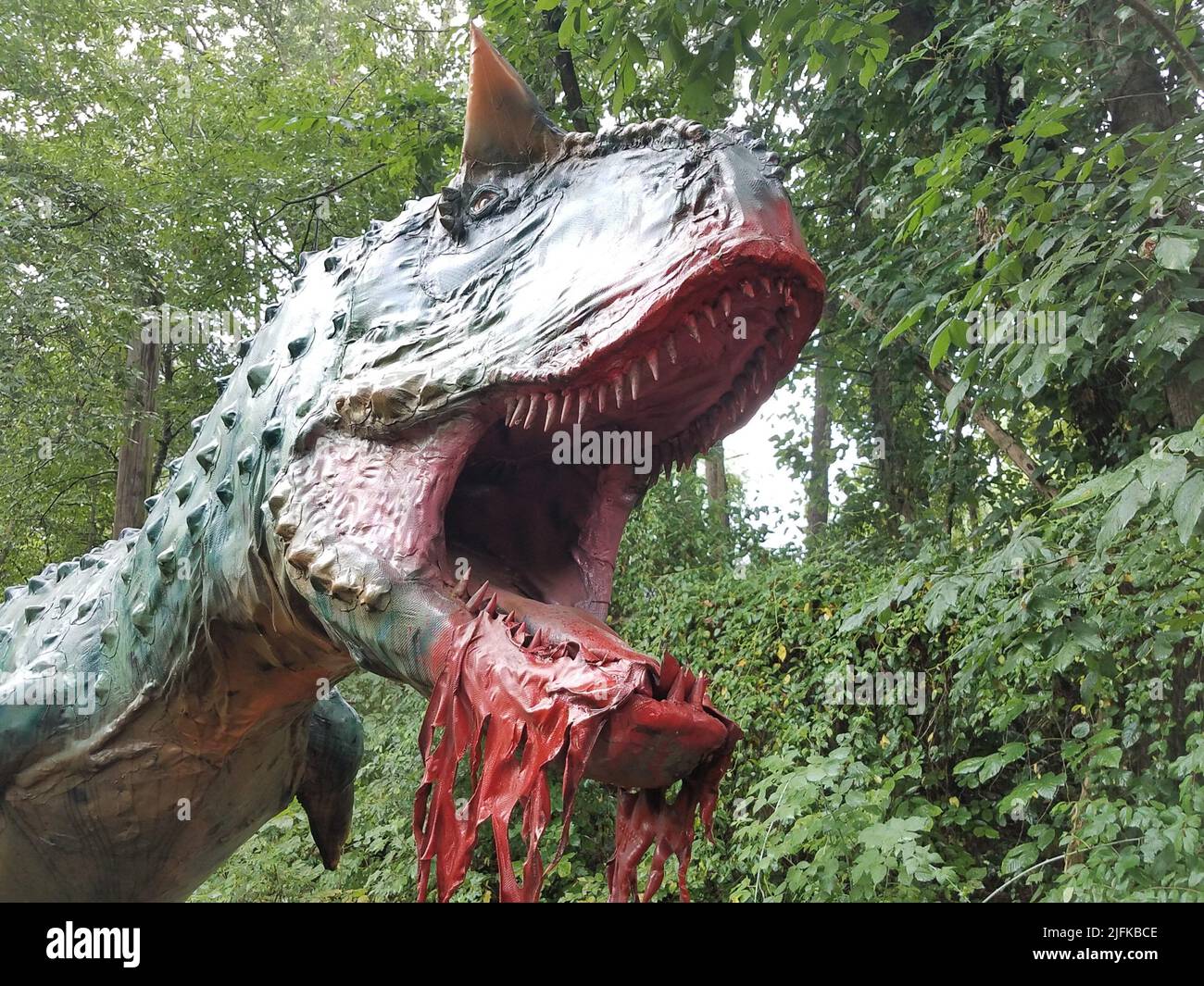 dinosaur with sharp teeth eating meat in the forest or woods Stock