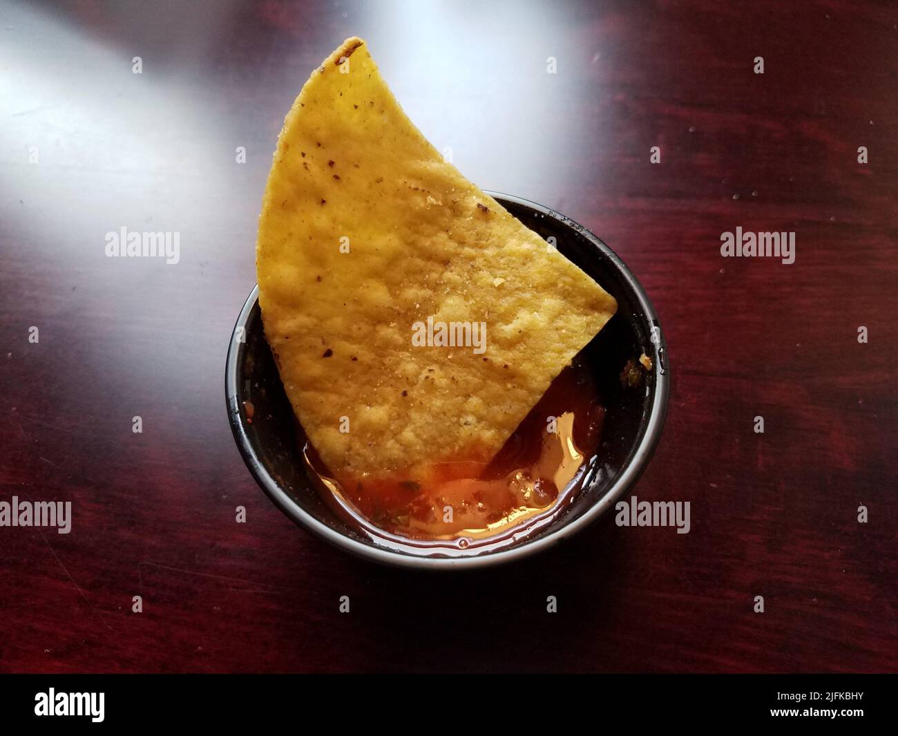 a single tortilla chip dipped in salsa cup Stock Photo Alamy