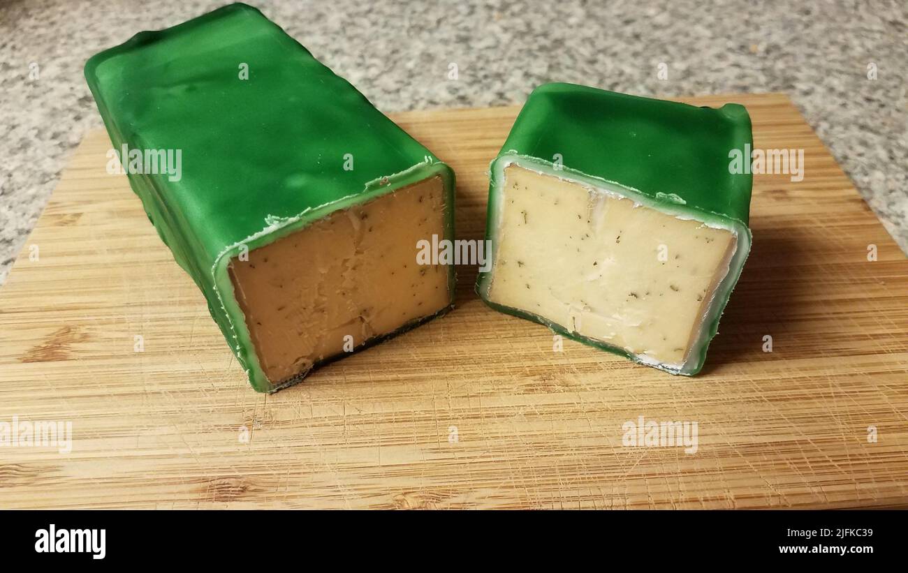 cut cheese encased or sealed in green wax on wood cutting board Stock