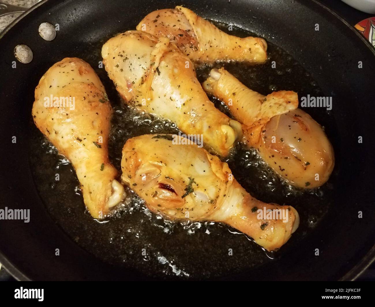 chicken drumsticks cooking in hot oil in skillet or frying pan Stock