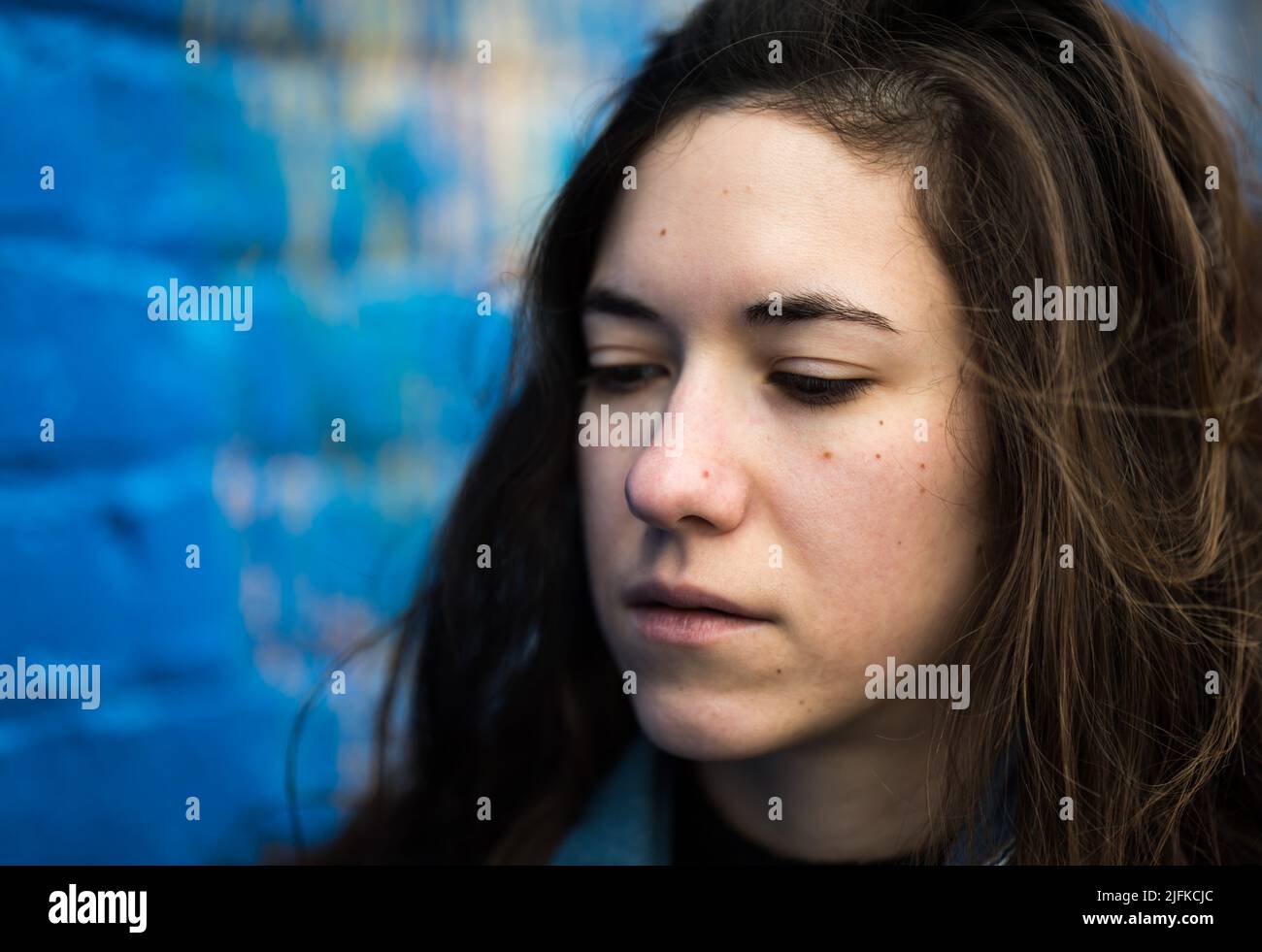Close Up Of An Attractive 27 Year Old Woman With Brown Hair Against A Blue Wall Brussels