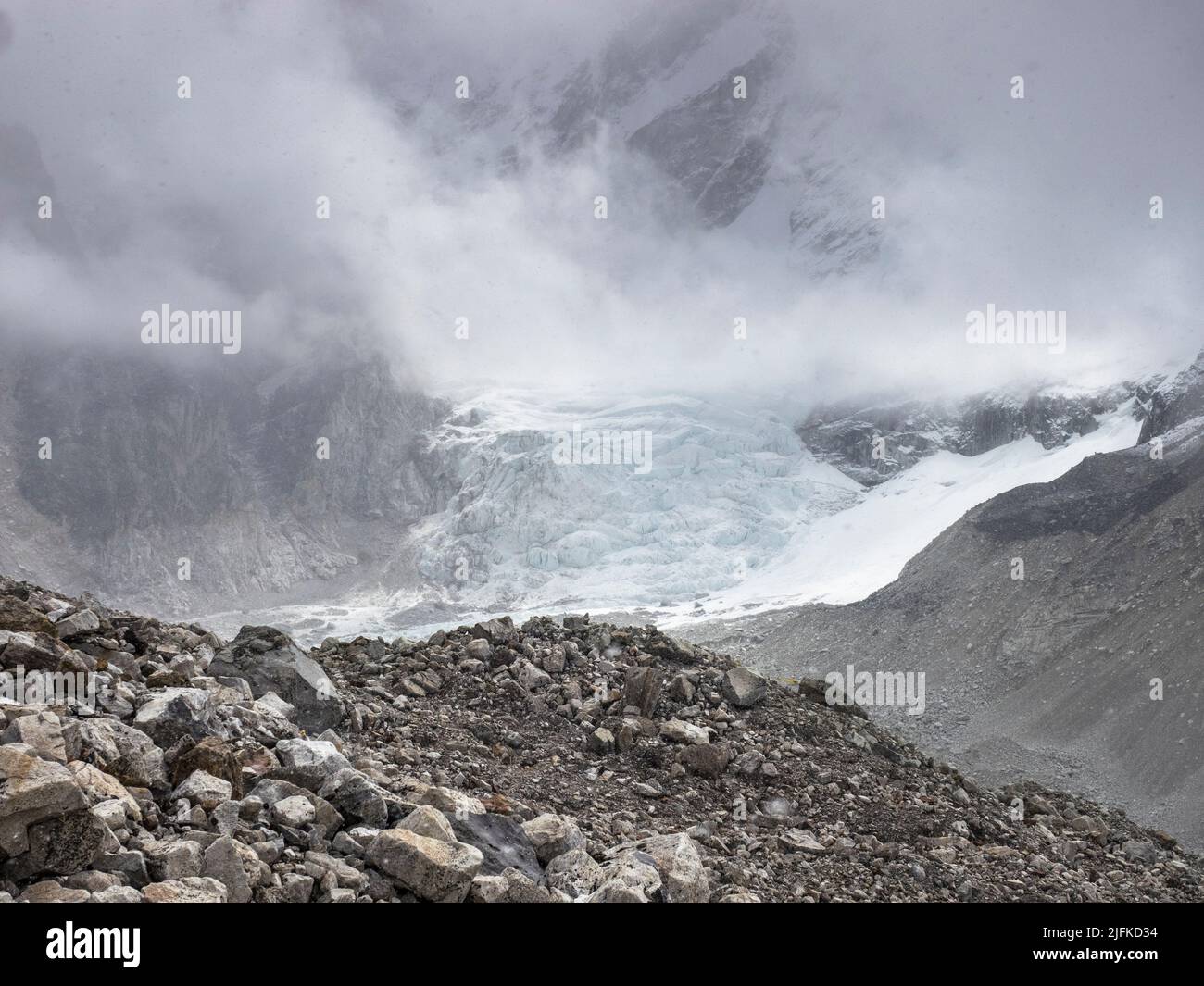 Low May clouds above  the Khumbu Glacier and an icefall off Nuptse on the trekking route along the moraine to Everest Base Camp. Stock Photo