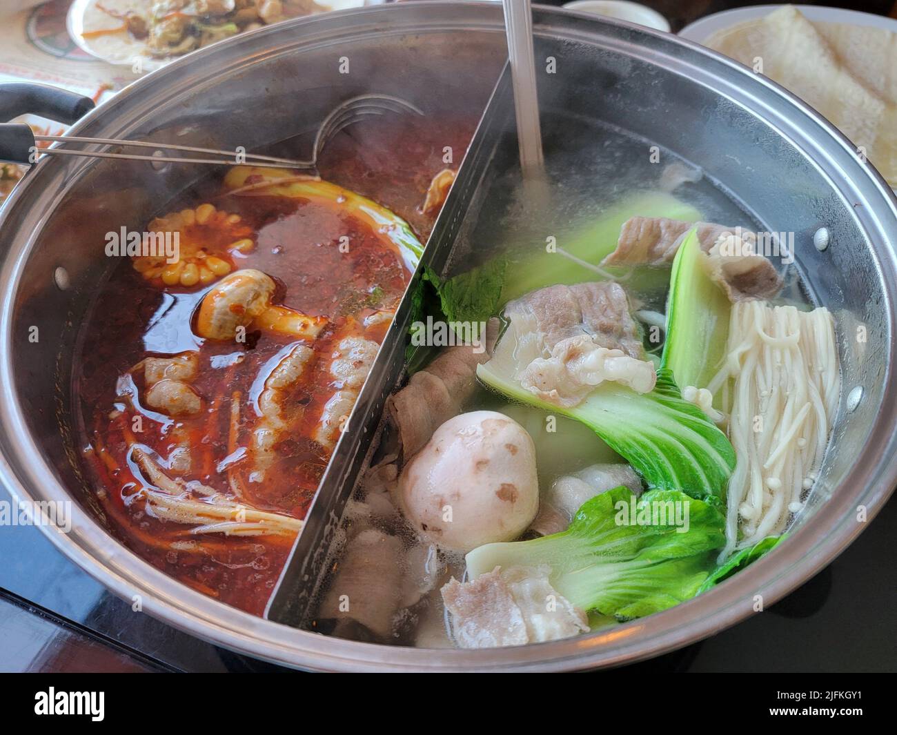 Chinese or asian hot pot with spicy and regular broth and meat and
