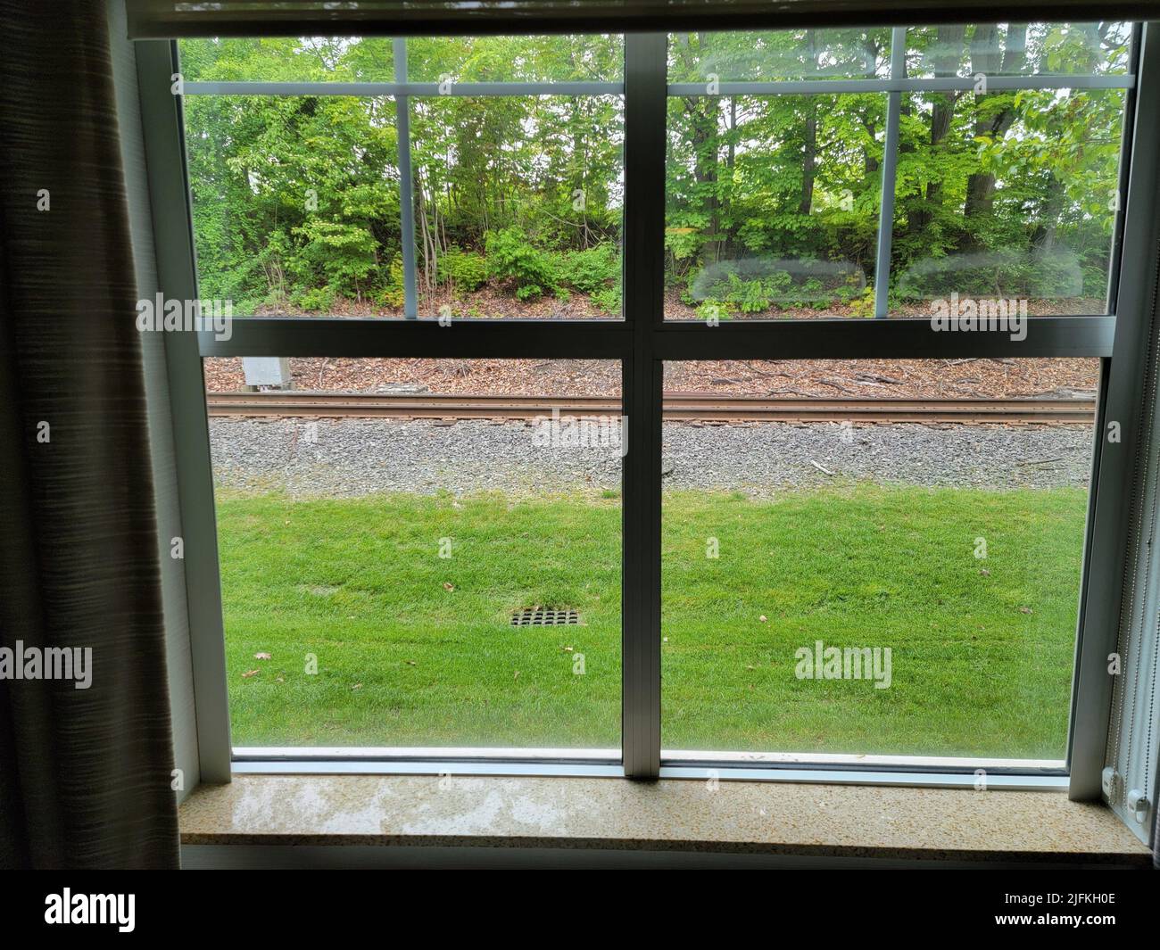 hotel or home window with railroad track and green grass. Stock Photo