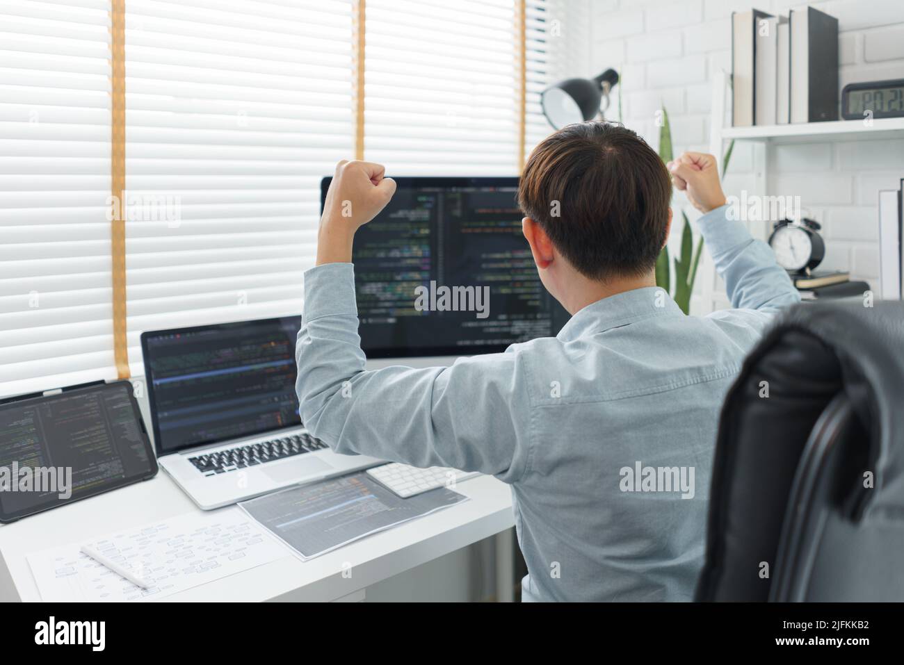 Software development concept, Male programmer excited and raise arms after successful programming. Stock Photo