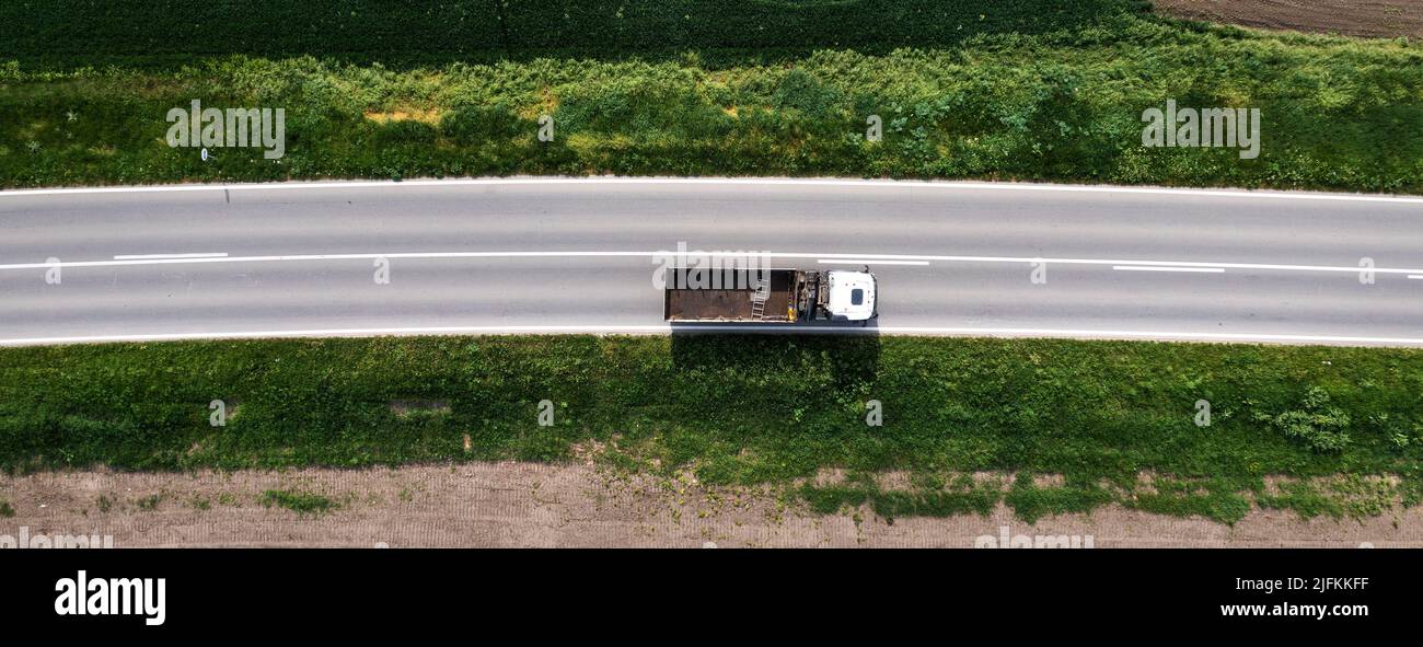 Top view aerial of semi-end dump truck with empty trailer on the road, drone pov Stock Photo