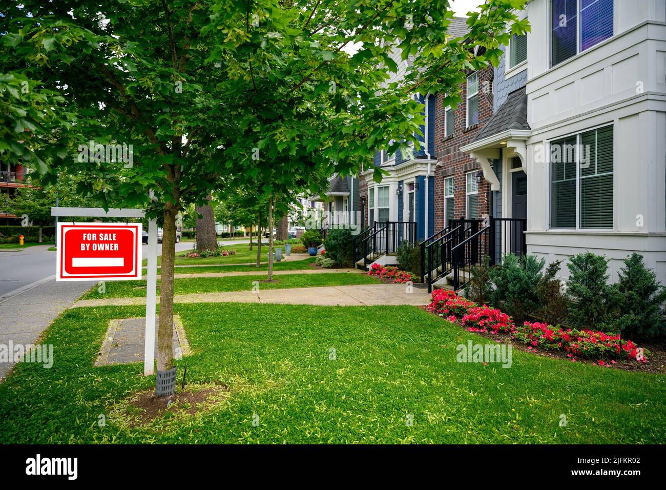 The marketing for sale sign boards of local estate agent outside homes on a street in a nice suburban neighborhood in British Columbia, Canada. Stock Photo