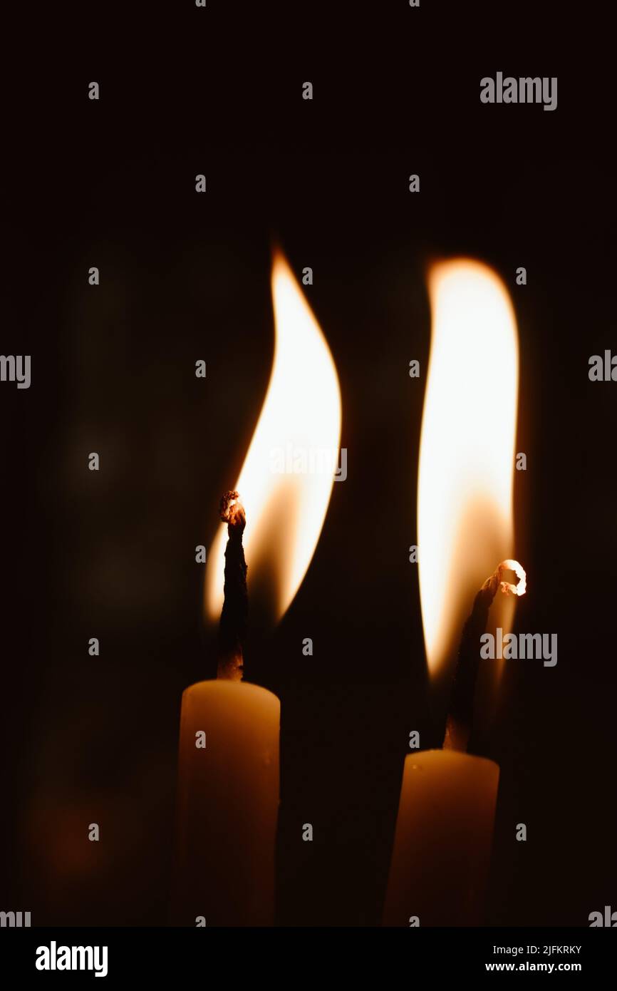 Candles burning with yellow flames in the dark Stock Photo Alamy