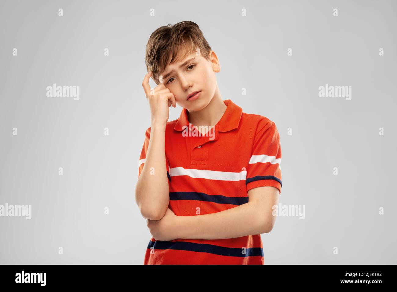 portrait of sad thinking boy in red polo t-shirt Stock Photo