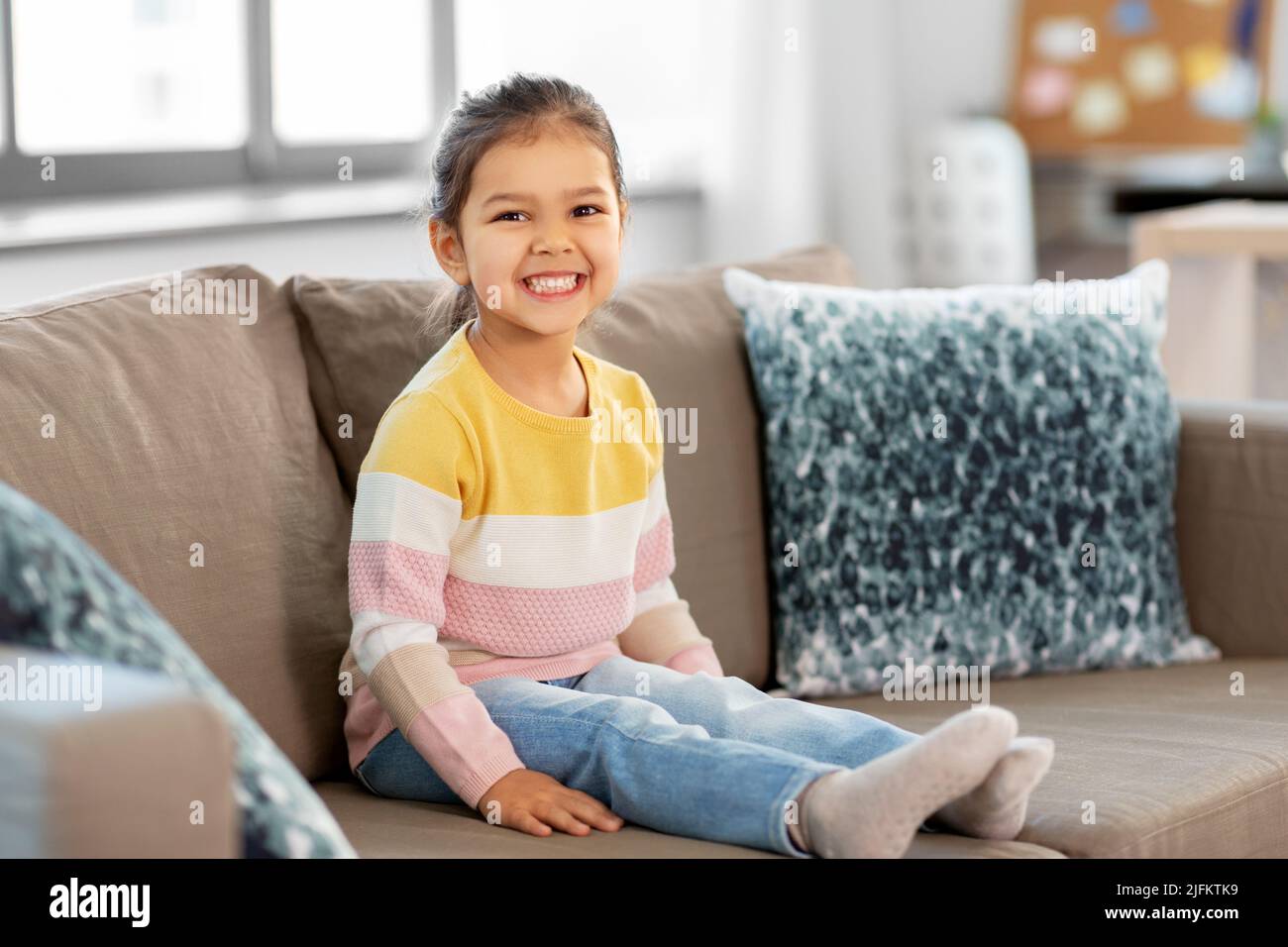 happy smiling little girl sitting on sofa at home Stock Photo - Alamy
