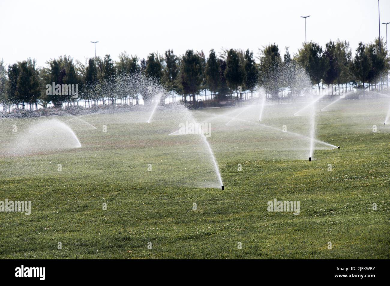 Lawn water sprinkler spraying water over grass in garden Stock Photo