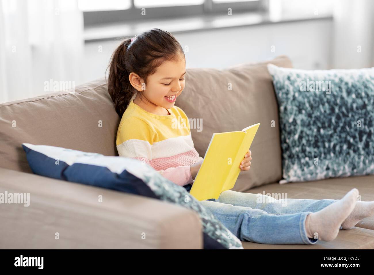 happy smiling little girl reading book at home Stock Photo - Alamy