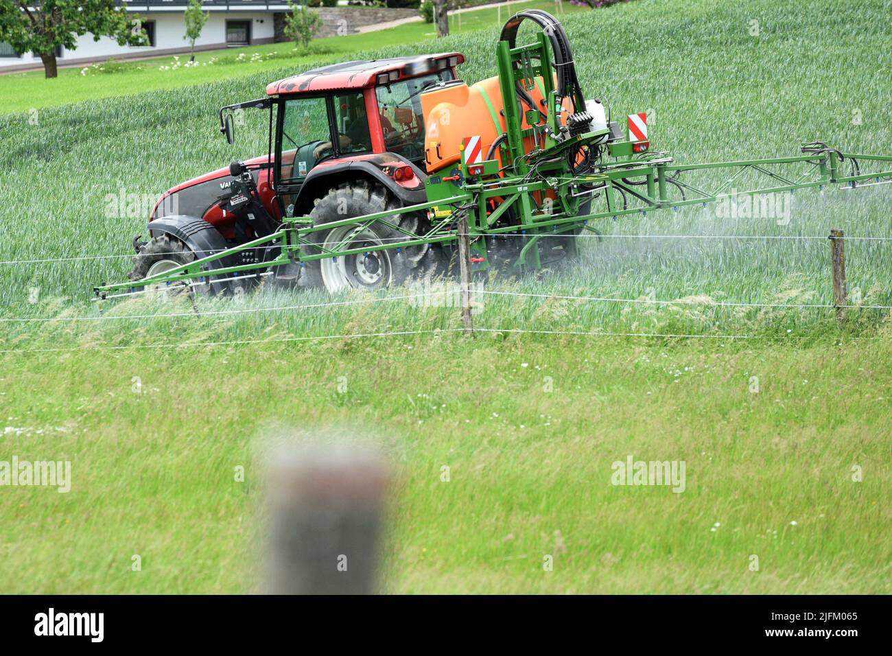 Traktor bringt mit Fass Pflanzenschutzmittel aus - Tractor applies pesticides with a barrel Stock Photo