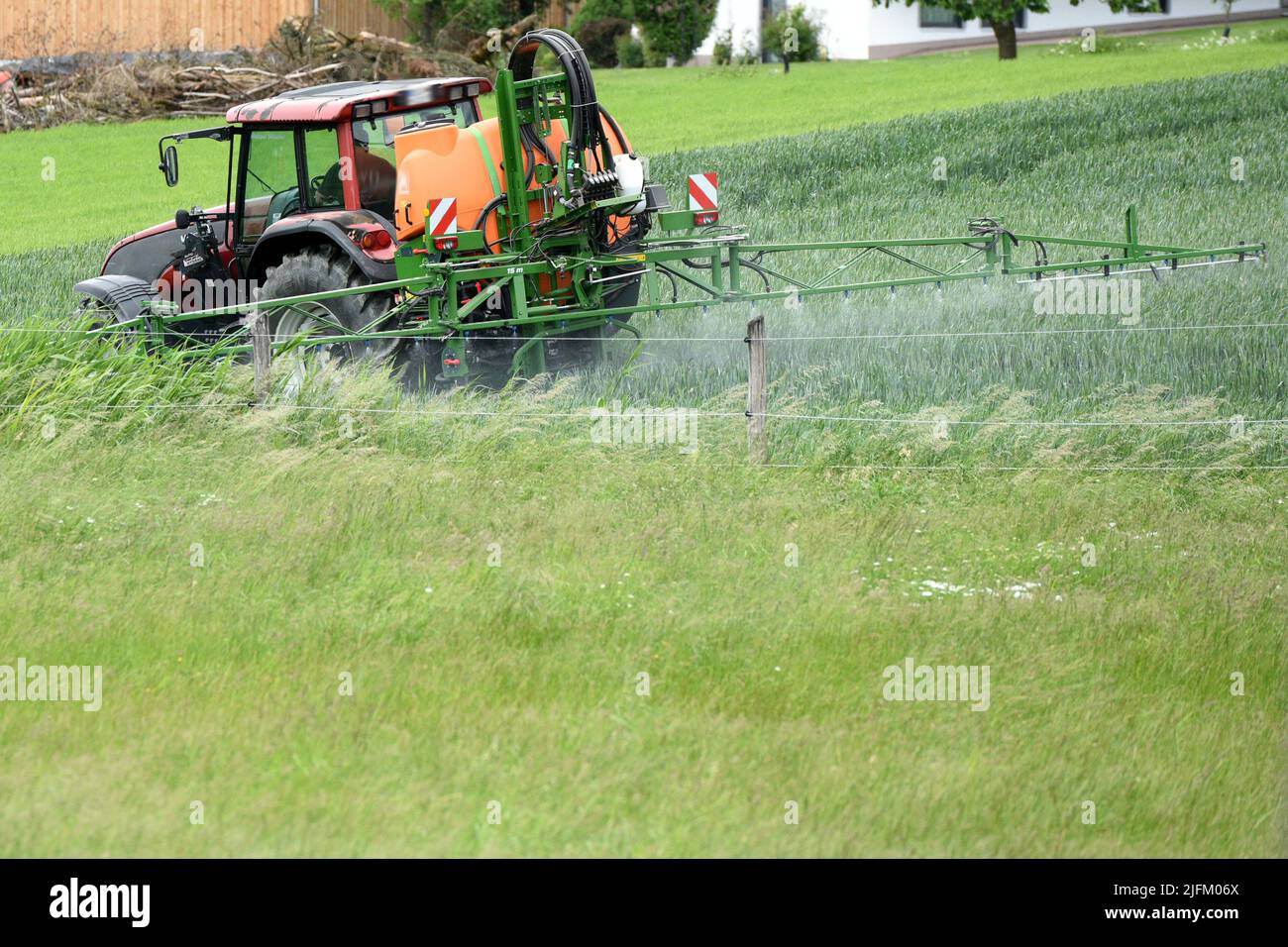 Traktor bringt mit Fass Pflanzenschutzmittel aus - Tractor applies pesticides with a barrel Stock Photo