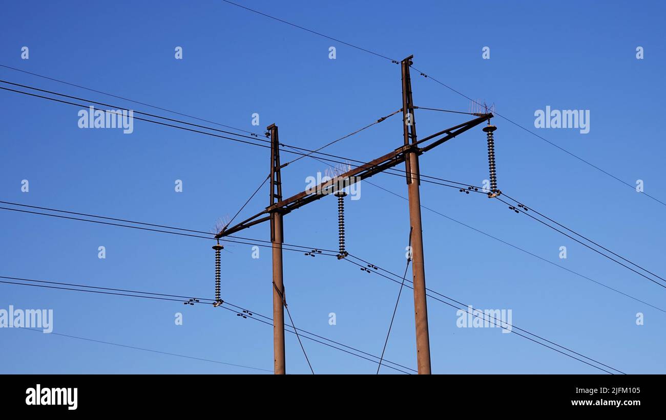 Poles with high voltage wires against the blue sky Stock Photo - Alamy