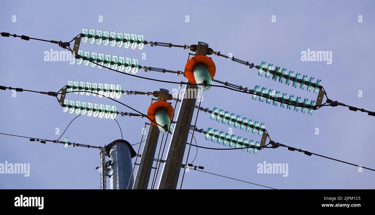 Poles with high voltage wires against the blue sky Stock Photo - Alamy