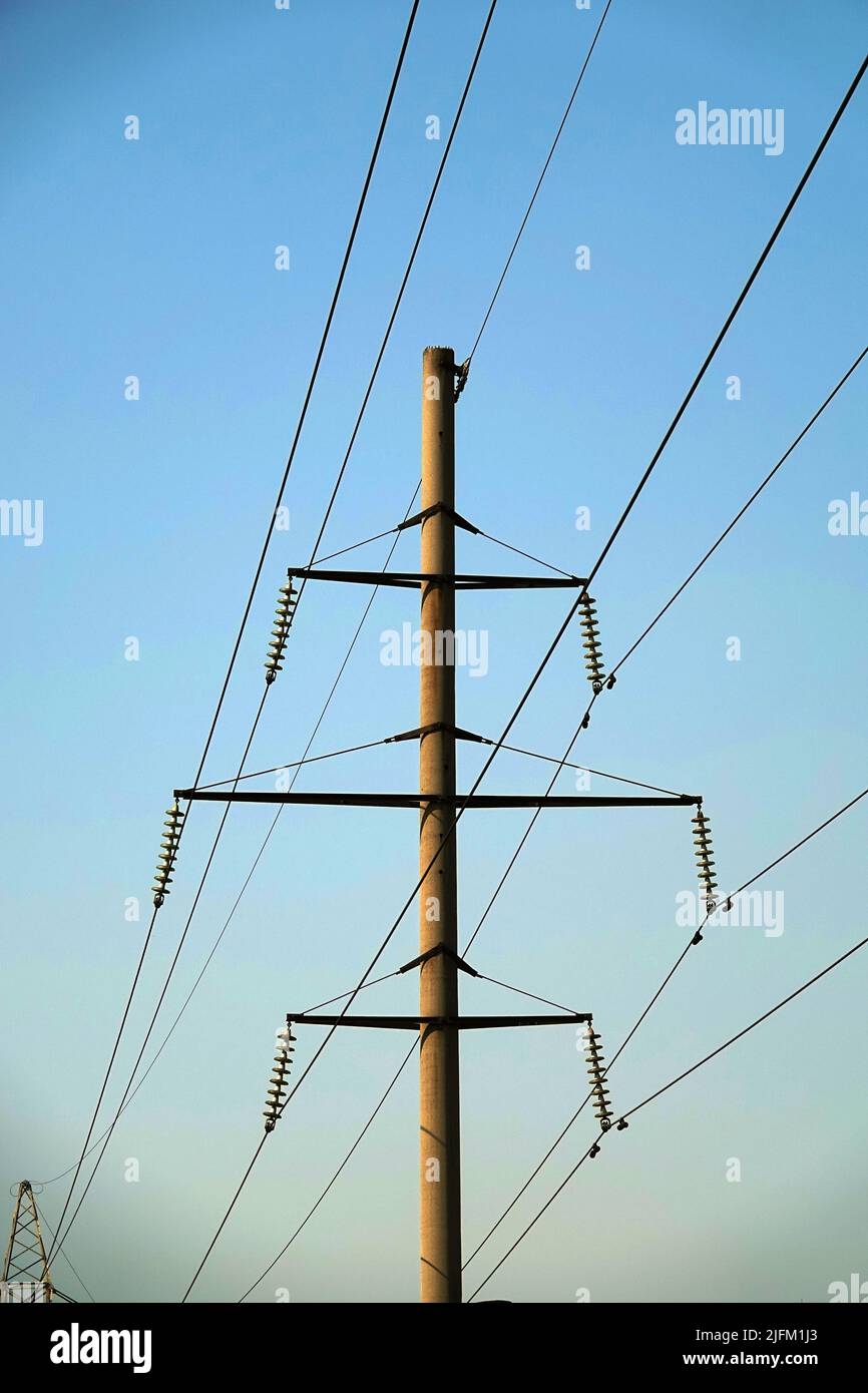 Poles with high voltage wires against the blue sky Stock Photo - Alamy