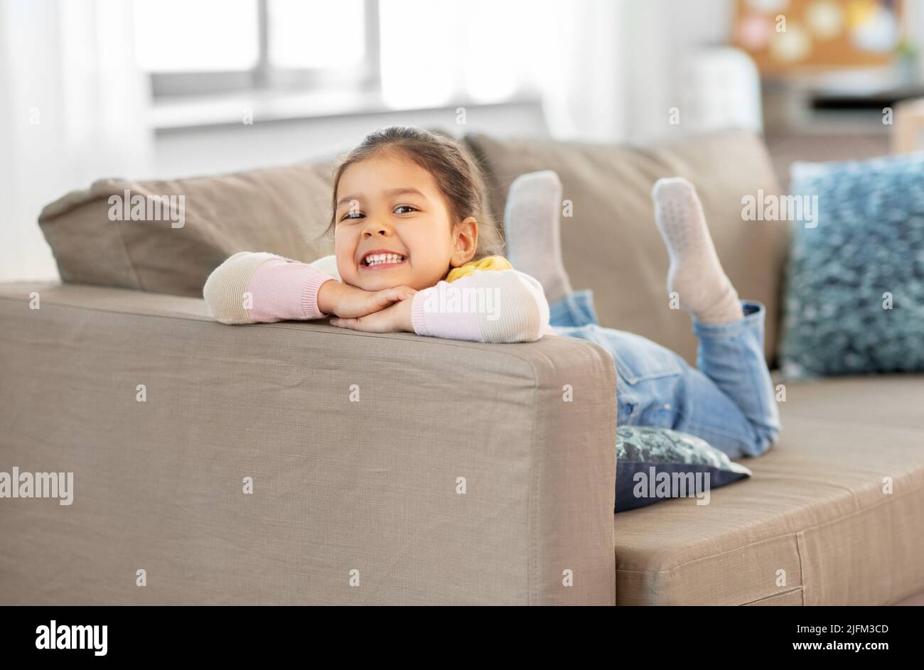 happy smiling little girl lying on sofa at home Stock Photo - Alamy