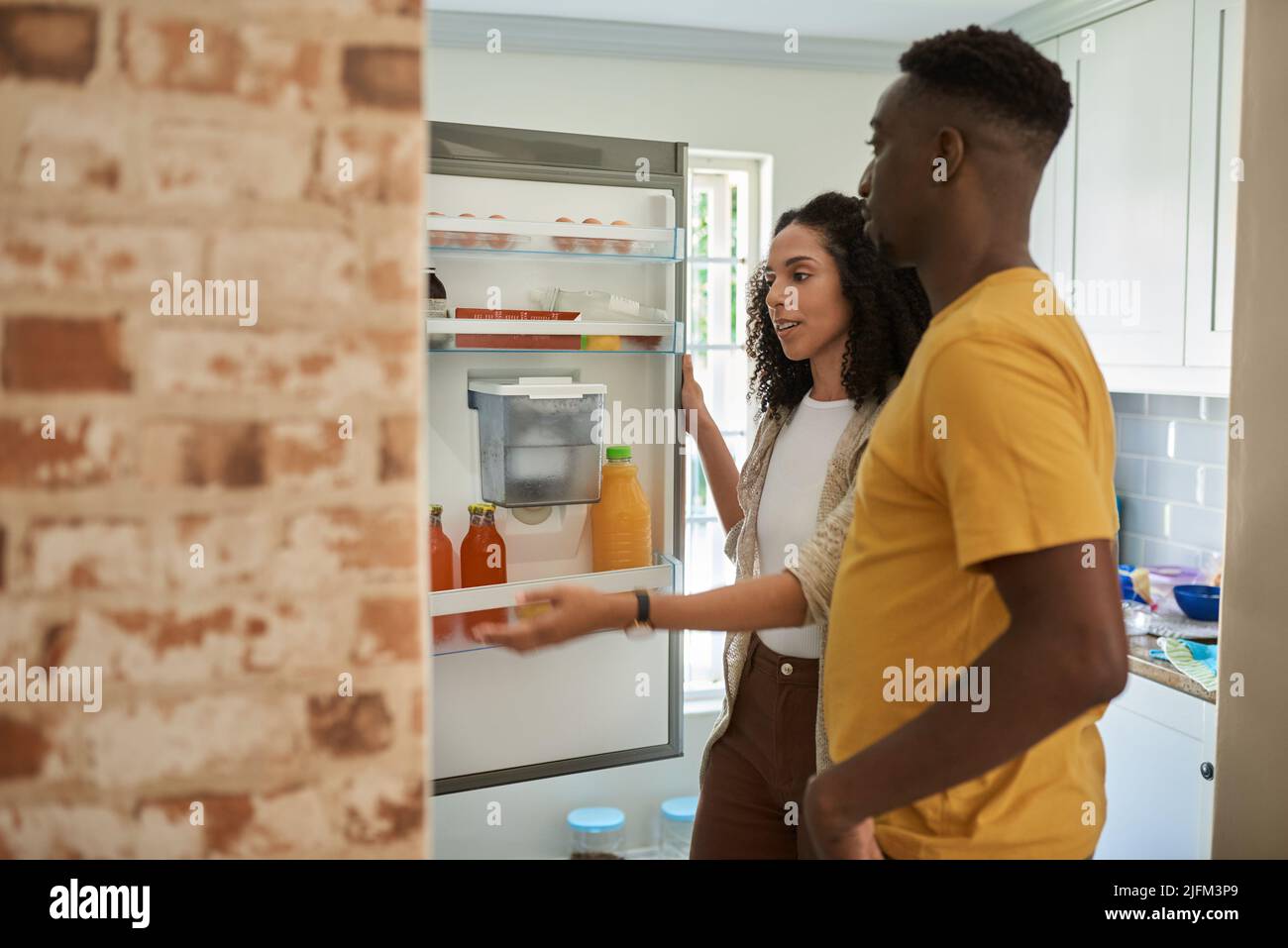 Young multiethnic couple looking for something in their kitchen fridge Stock Photo