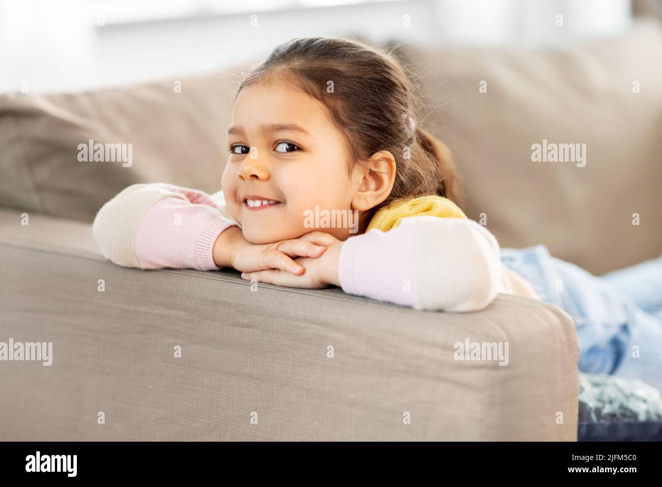 happy smiling little girl lying on sofa at home Stock Photo - Alamy