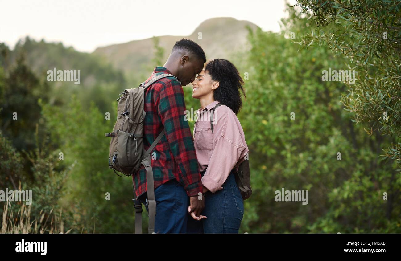 Young multiethnic couple standing face to face with their eyes closed on a trail during a break from hikine in some hills in the summertime Stock Photo